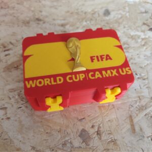 Caja para cromos del Mundial de fútbol roja y amarilla sobre mesa de madera
